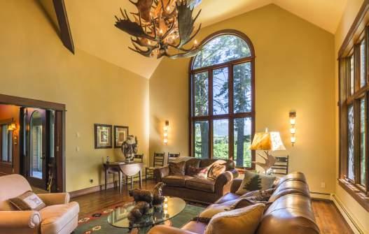 The front entry s two-story-high vaulted ceiling continues into the formal living room, showcasing west windows to the Bridger Mountains and a north view of the woods.