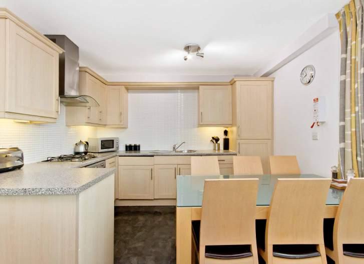 The well-appointed kitchen is equipped with ample fitted storage and workspace, plus integrated appliances including a four-burner gas hob with an overhead extractor hood, an electric single