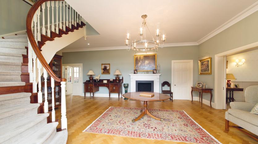 The attractive regency front door leads into the ENTRANCE HALL with the curving staircase fireplace and parquet floor.