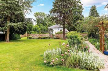 The mature gardens surround the house with manicured lawns and perennial borders and shrubberies.