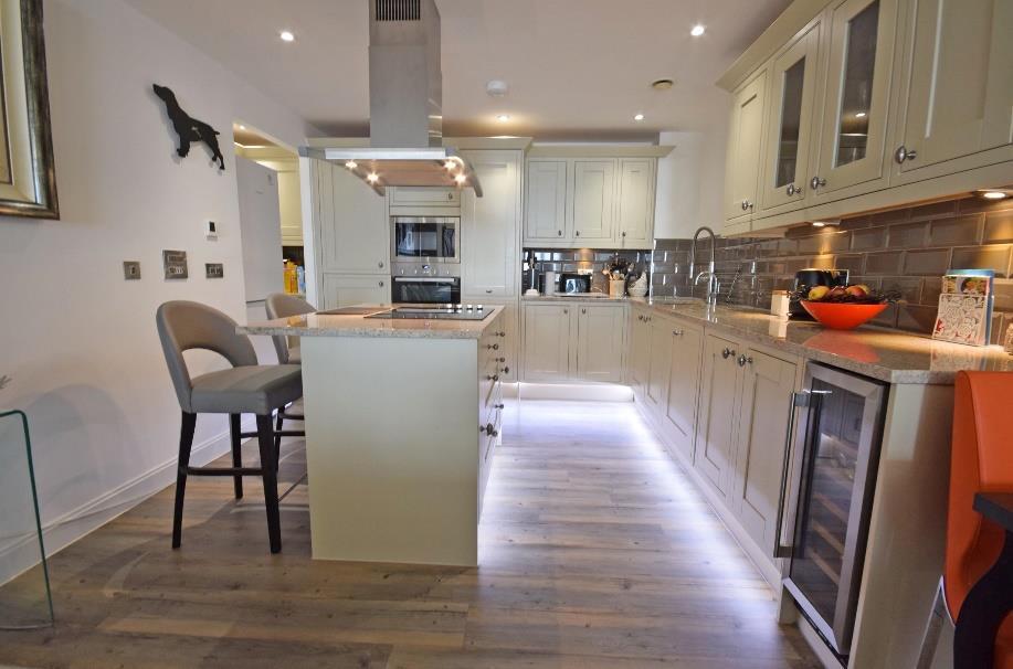 Surrounding honed granite worktop surfaces with complementary tiled wall surrounds and pelmet lighting to the worktops.