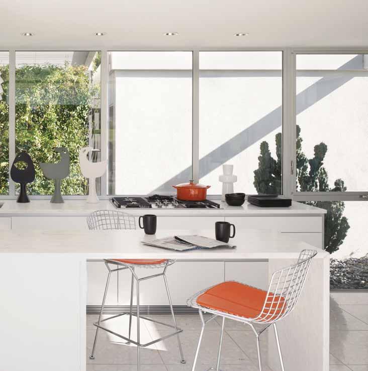 A vintage Max Sauze Orion chandelier from 1967 hangs above the kitchen island, beyond which is an enclosed garden. The counter stools were designed by Harry Bertoia for Knoll.