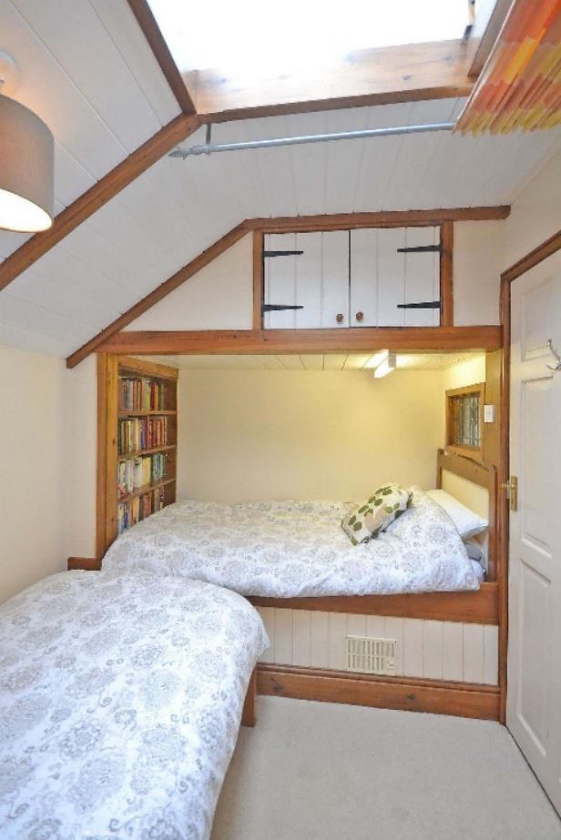 An exciting bedroom with a built-in double bed beneath a mezzanine dressing area and 12 high painted wood boarded ceiling.