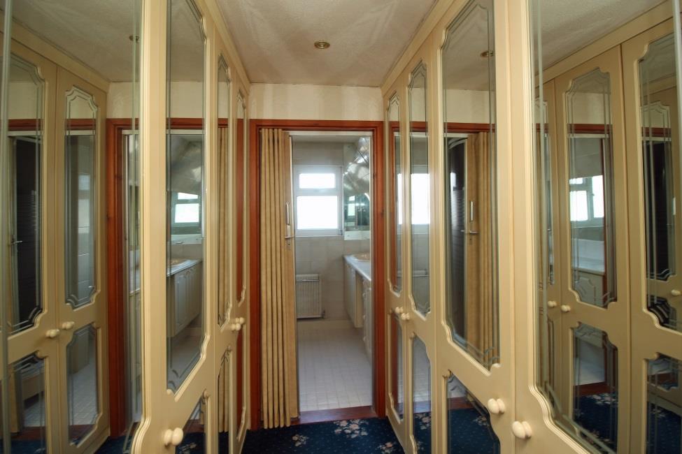 Archway to: Dressing room Fitted with a four door run of mirror fronted wardrobes on either side.