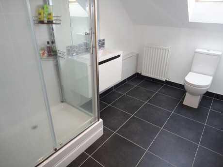 Shower room Velux window to front aspect, fitted storage cupboards, white suite comprising low flush WC, floating wash hand basin with vanity unit under, shower cubicle with