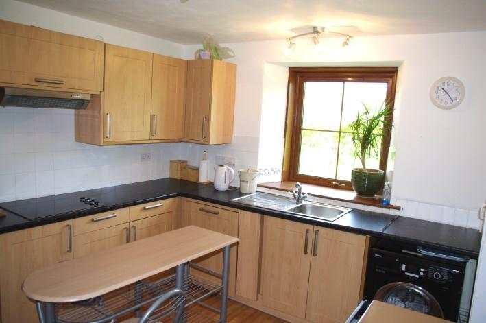 Electric fitted hob with extractor hood above. Fitted oven and microwave. Large selection of wall and base cupboards. Wood panelling to dado level.