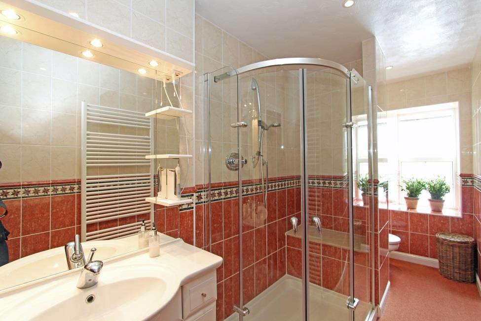 comprising large shower cubicle with built in seat, basin set in vanitory unit with