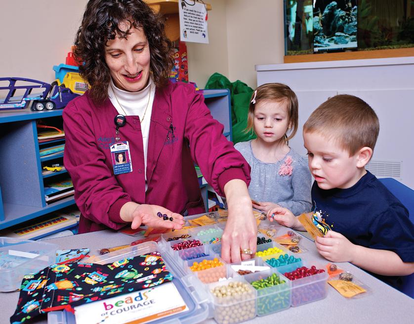 EMMC child life specialist Amy Baker helps patients Maggie and Devin select their beads.