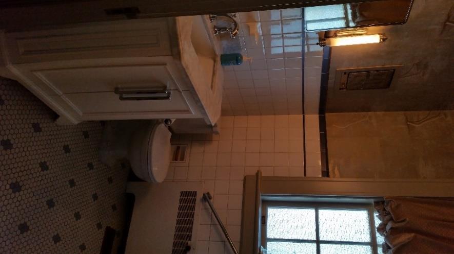 Old original sidelights over sink, white tile with blue trim, floor is white with a few blue tiles sprinkled in.