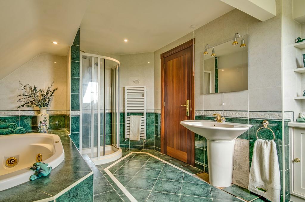 from a feature Jacuzzi style bath and a separate shower. There is plenty of storage throughout by way of cupboards and a spacious walk-in shelved hotpress.