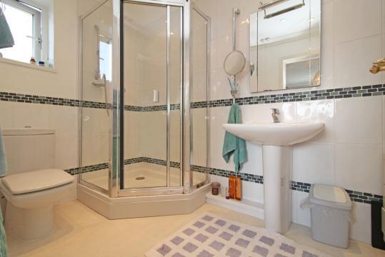 Mixer shower over and tri fold glazed shower panel. Half tiled walls, coving and recessed halogen lighting.