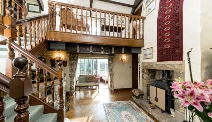 A second set of double doors lead into the bright entrance hall which has a vaulted ceiling, feature inglenook fireplace housing a multi-fuel stove, stone bar, attractive parquet flooring and doors