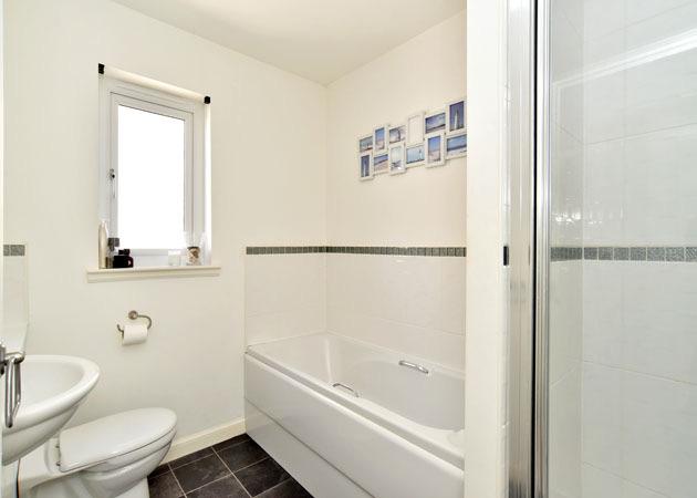, set into bathroom furniture providing toiletry storage and display areas, bath, tiled splashbacks and matching shower tray set into a tiled shower area with fitted