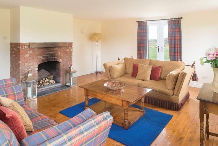 SITTING ROOM with triple aspect, exposed wood floor, French doors to side, brick fireplace suitable for open fires.