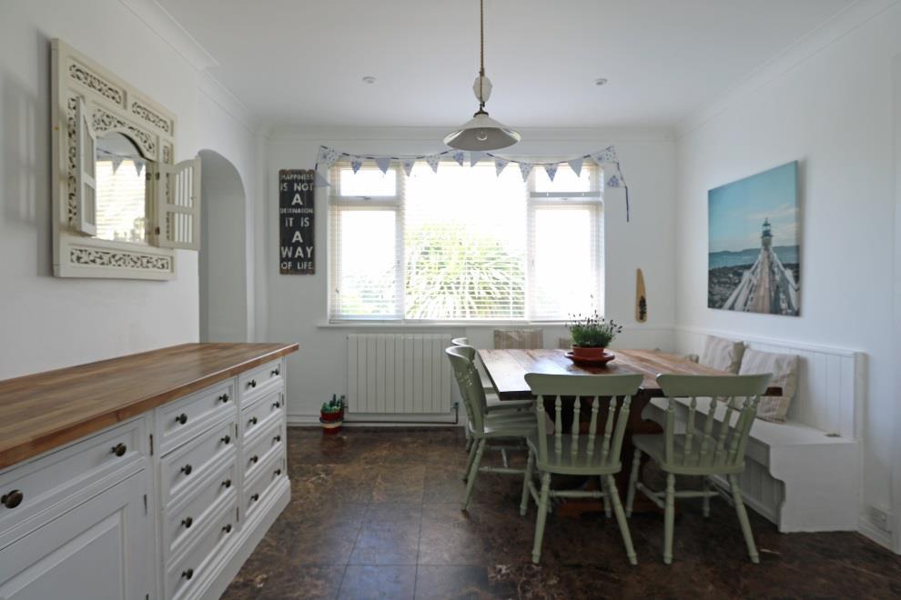 Space for large dining table and chairs, fitted corner bench with storage below. Polished ceramic tiled flooring with underfloor heating. Fully glazed French doors leading out to the rear garden.