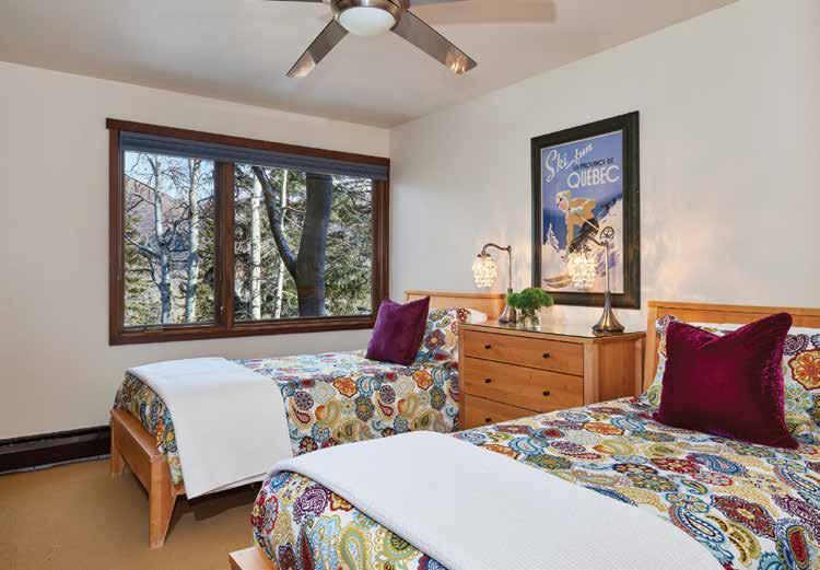 The downstairs guest bedroom with two twin beds has a soothing décor, walk-in