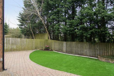 Side and enclosed rear garden in paviors with artificial grass