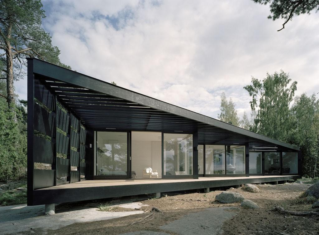 of the black stained exterior relates to the verticals of tall grown pines and the mirrored views of the Baltic Sea The geometry of the plan is generated by the specifics of the site, the house being