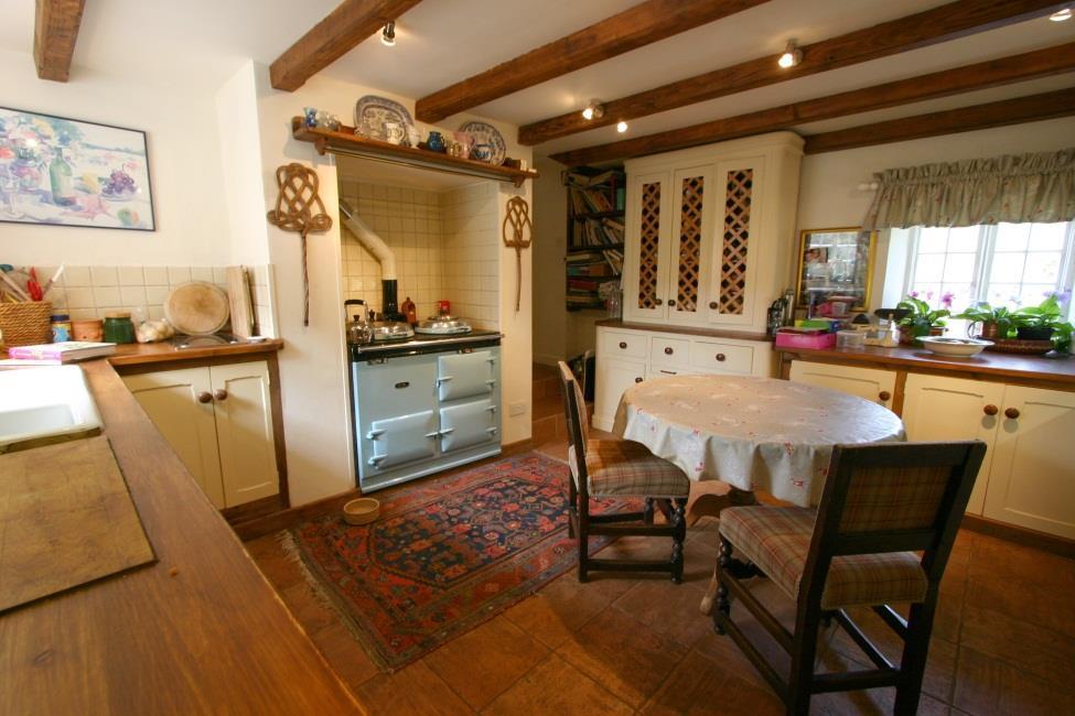 Door and step up to Kitchen: 14 3 x 12 10 Cream coloured conventional wooden kitchen complete with Aga. Beamed ceiling.