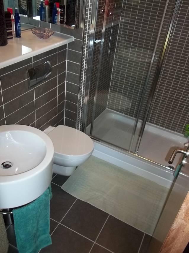 EN SUITE Approx: 5 5 x 7 Fitted with a white suite comprising WC, wash hand basin and double shower. Porcelanosa duo tiling. Complementary floor tiles. Chrome towel radiator. Expelair fan.