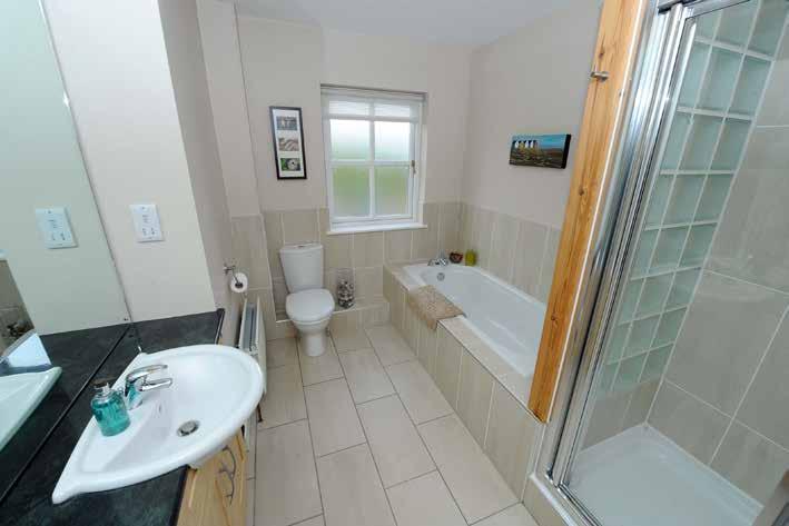 BATHROOM: Contemporary white suite comprising panelled bath with mixer tap, separate fully tiled