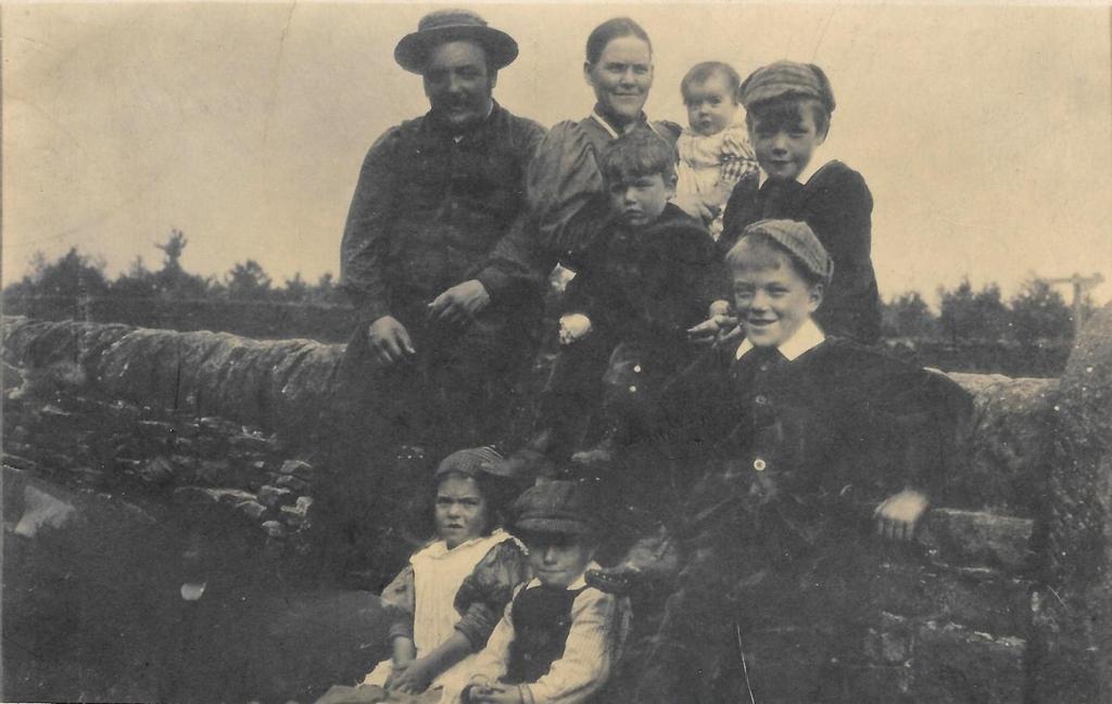 The Slack family on Silsden Moor, c. 1896-7 Stood at the back: Richard Henry, Lily (holding Mary). Sat on the wall: Peter, William. Sat against the wall: Martha Ann, Charles. Stood at front: Richard.