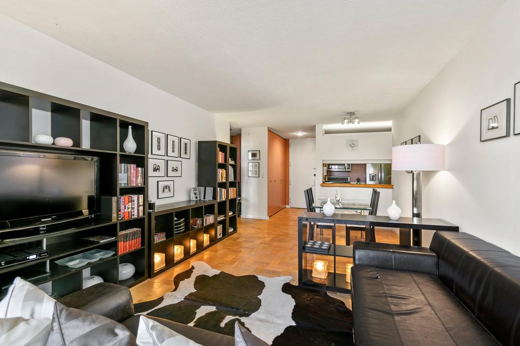 A west-facing, 720-square-foot condo with parquet floors, a pass-through kitchen and a walk-in closet, in a 1980s doorman building with an indoor track and two roof decks.