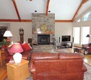 The great room features a vaulted ceiling with wood beams, hardwood floors, a woodburning fireplace and a wall