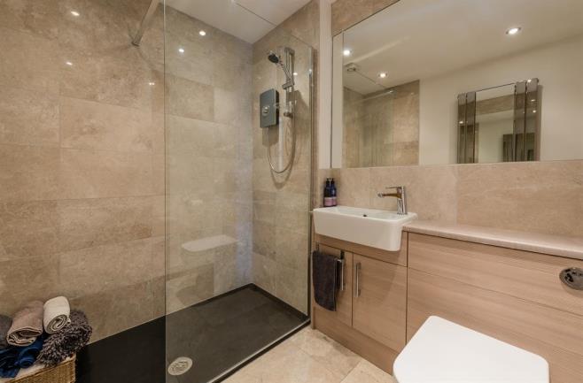 with fitted wall mirror, full length mirrored radiator, recess spotlights, extractor fan and marble flooring.