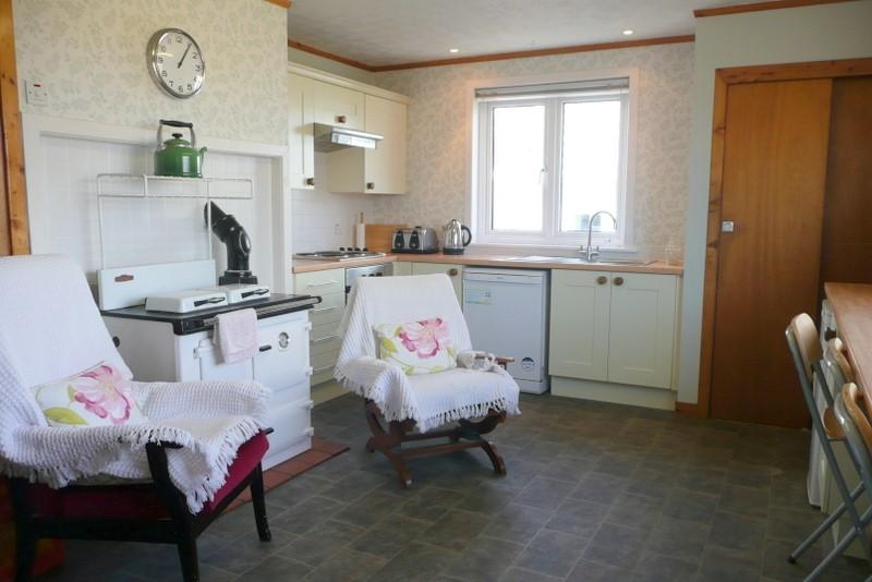 The kitchen is fitted with cream floor and wall units, stainless steel sink, an electric oven, hob