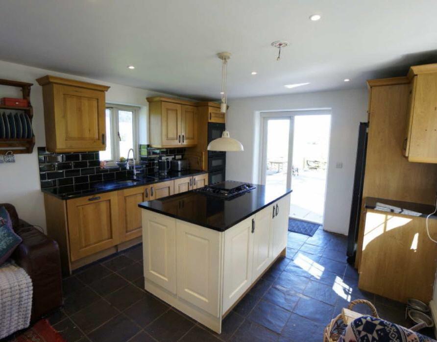 81m) Kitchen: Range of base and wall units with granite worktops over; central island with 5 ring gas hob, split level double oven and grill; integrated microwave; wall tiling; American style fridge